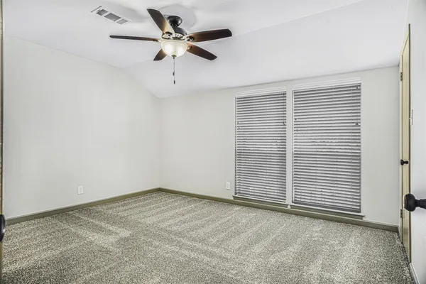 an empty room with a ceiling fan and a window