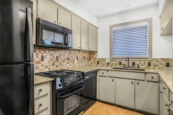 a kitchen with granite countertop a sink stainless steel appliances and cabinets