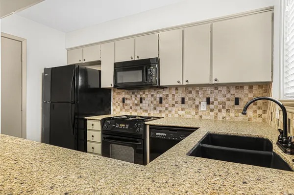 a kitchen with stainless steel appliances a sink a stove a microwave a sink a refrigerator and cabinets