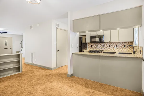 a view of kitchen with granite countertop cabinets and refrigerator