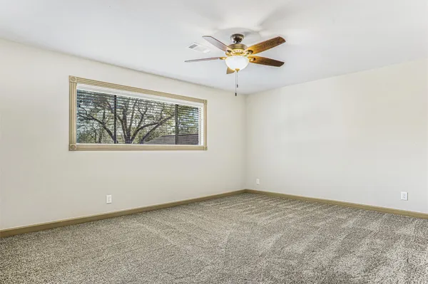 an empty room with a window and a fan