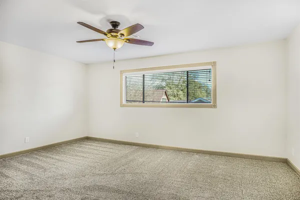 an empty room with a window and a ceiling fan