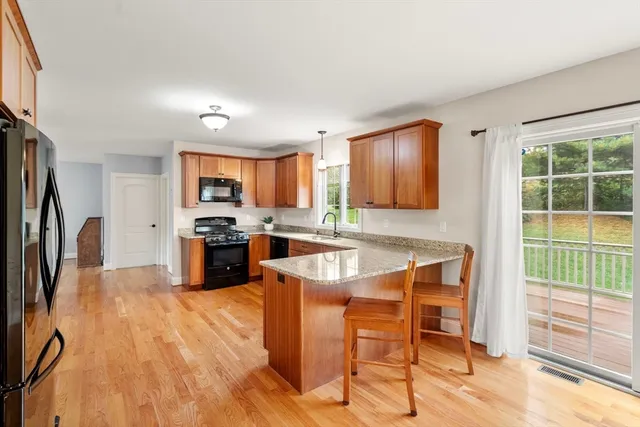 a kitchen with stainless steel appliances granite countertop a refrigerator a stove top oven and a sink with cabinets