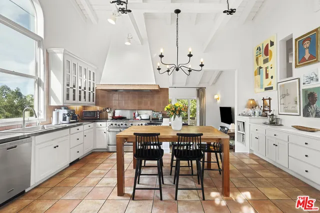 a kitchen with granite countertop stainless steel appliances a dining table chairs sink and cabinets