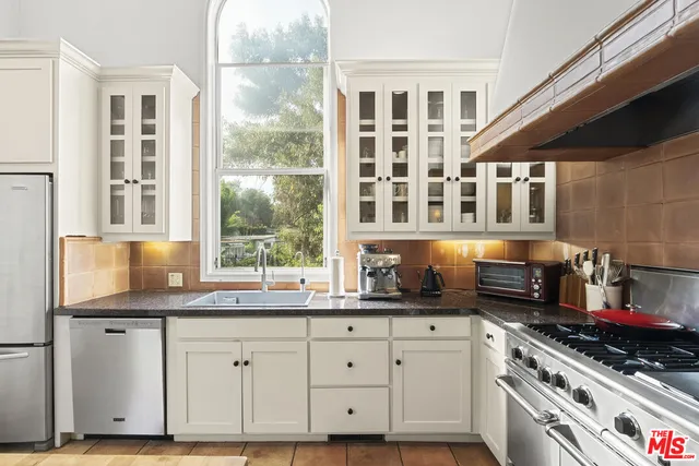 a kitchen with stainless steel appliances granite countertop a sink a stove and a wooden cabinets