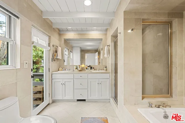 a spacious bathroom with a double vanity sink a mirror a bathtub and next to a window