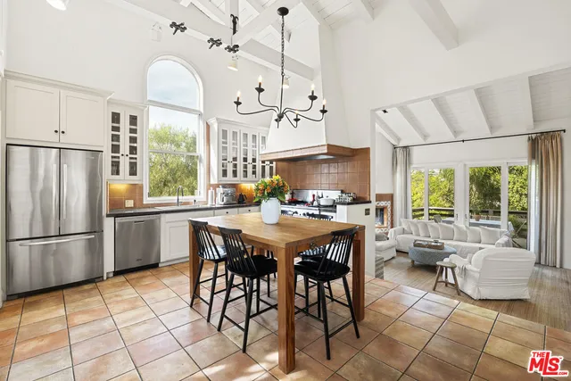 a kitchen with stainless steel appliances granite countertop a stove a refrigerator a oven a sink with a dining table and chairs