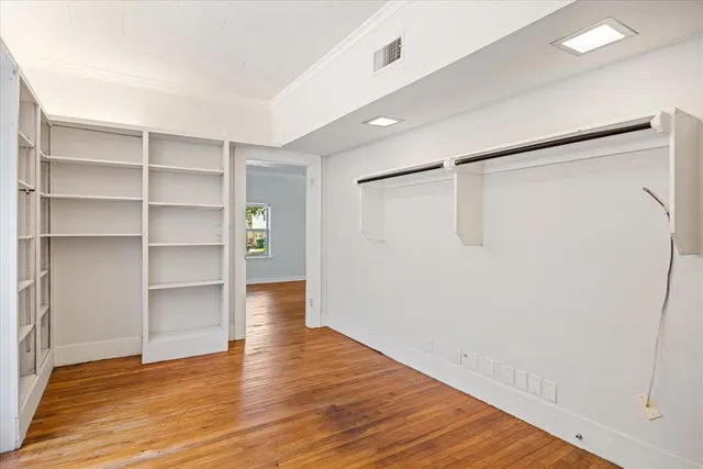 a view of an empty room with a window and wooden floor