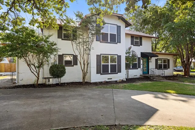 a white house that has a tree in front of it