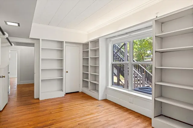 a view of an empty room with a window and wooden floor