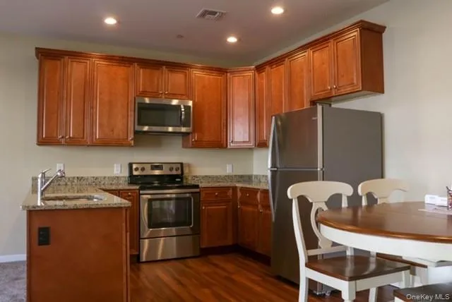 a kitchen with stainless steel appliances granite countertop a refrigerator a stove top oven a sink and dishwasher