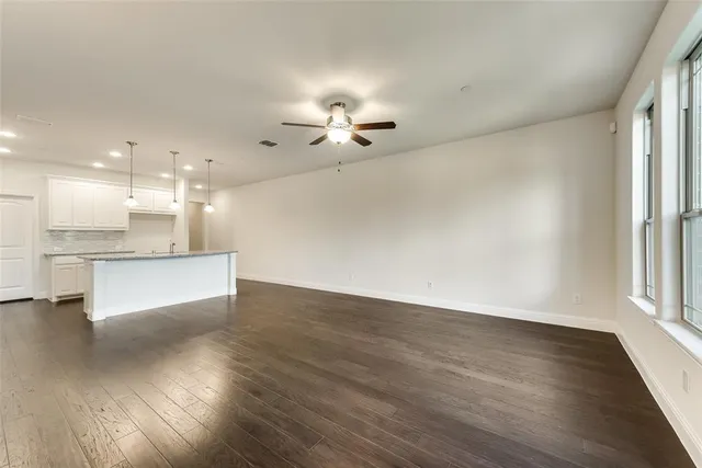 a view of an empty room with kitchen and kitchen view