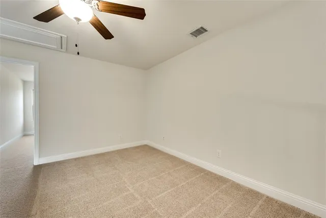 an empty room with a ceiling fan and carpet
