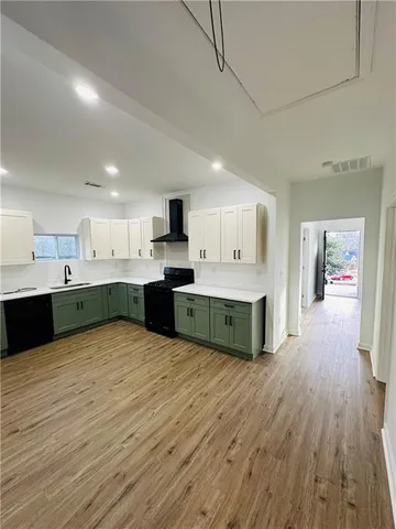 a large kitchen with kitchen island a sink dishwasher stove and white cabinets with wooden floor