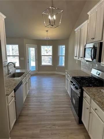an empty room with a chandelier fan and windows
