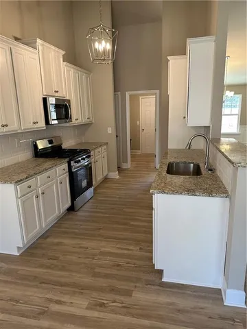 an empty room with wooden floor a ceiling fan and kitchen view