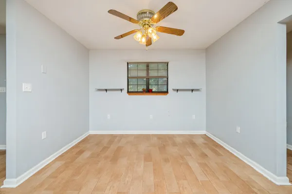 an empty room with a window and a fan