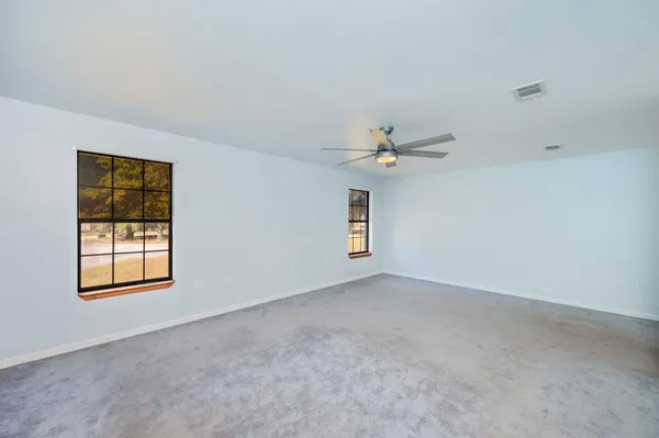 an empty room with windows and fan