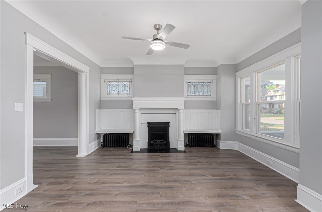 1229 Melbourne Road Cleveland, OH 44112 - Photo 5 of 22 Unfurnished living room with wood finished floors, radiator, ceiling fan, and a fireplace with flush hearth