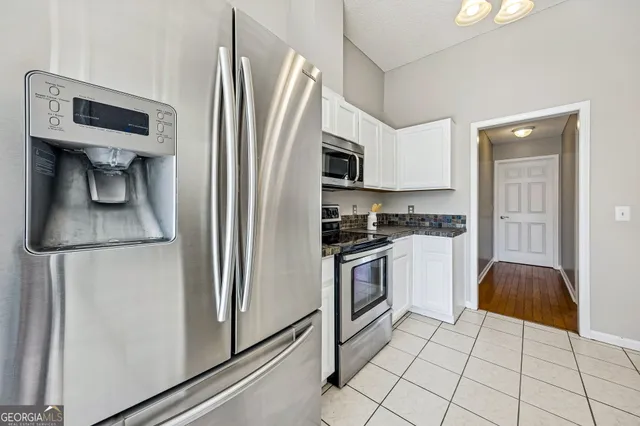 a kitchen with granite countertop a refrigerator and a stove top oven