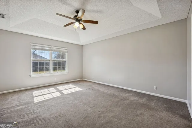 an empty room with windows and fan
