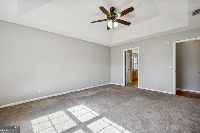 an empty room with windows and fan