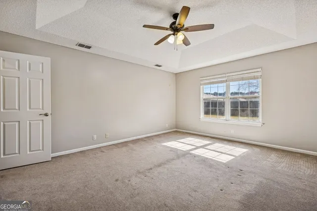 an empty room with windows and ceiling fan