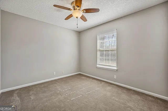 an empty room with a window and a fan