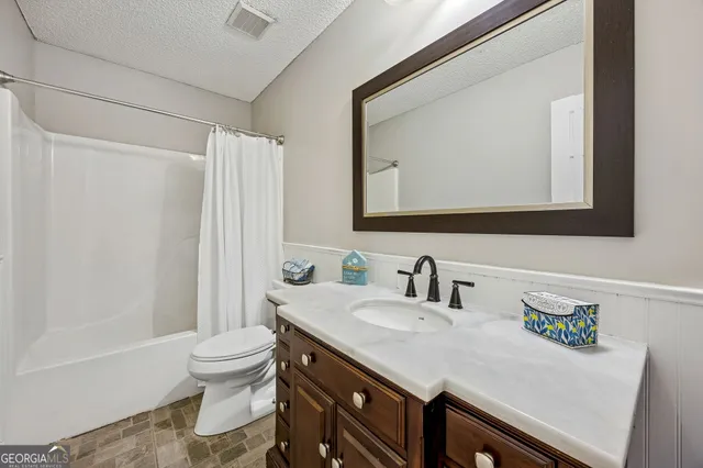 a bathroom with a granite countertop sink a toilet and a mirror