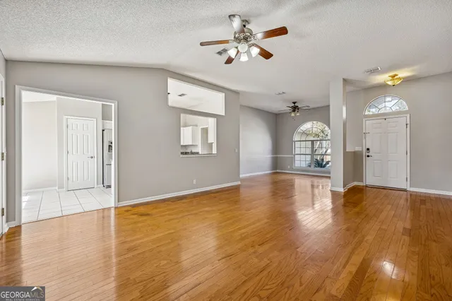 a view of empty room with wooden floor and fan
