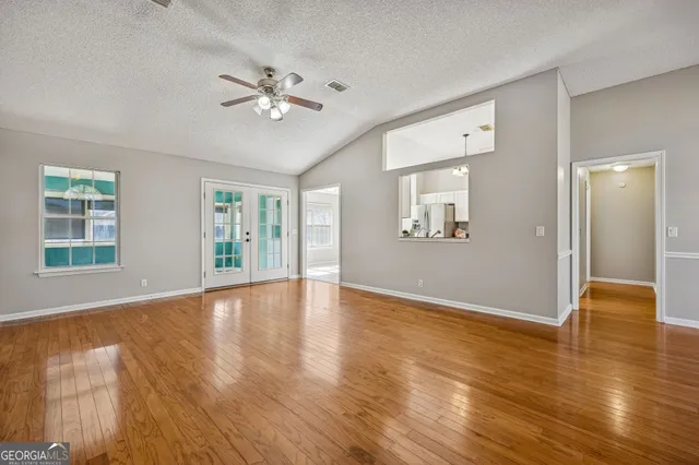 a view of an empty room with wooden floor and a window