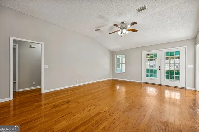 a view of empty room with wooden floor and fan