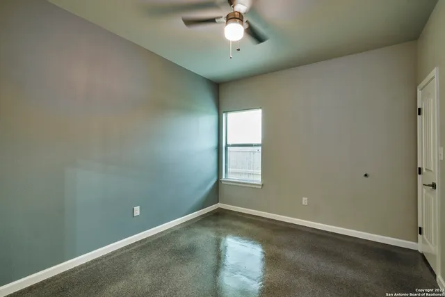 an empty room with a ceiling fan and window