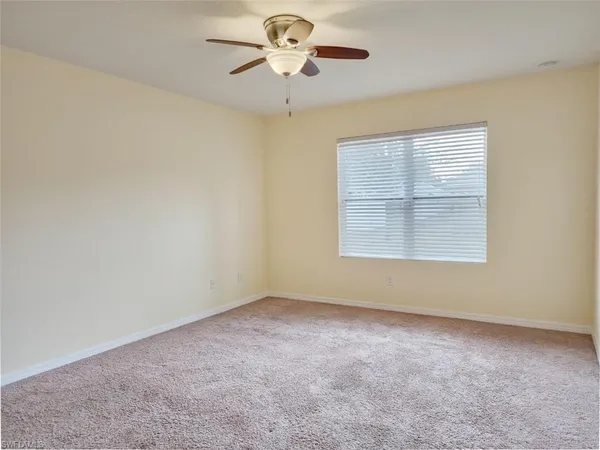 an empty room with a window and a ceiling fan