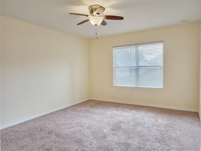 an empty room with a window and a ceiling fan