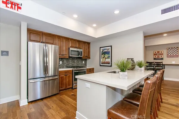 a kitchen with a refrigerator a stove a sink dishwasher a dining table and chairs with wooden floor