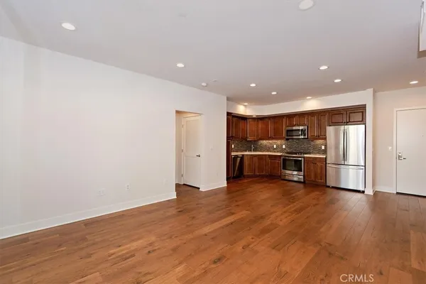 a kitchen with stainless steel appliances wooden floor and a large window