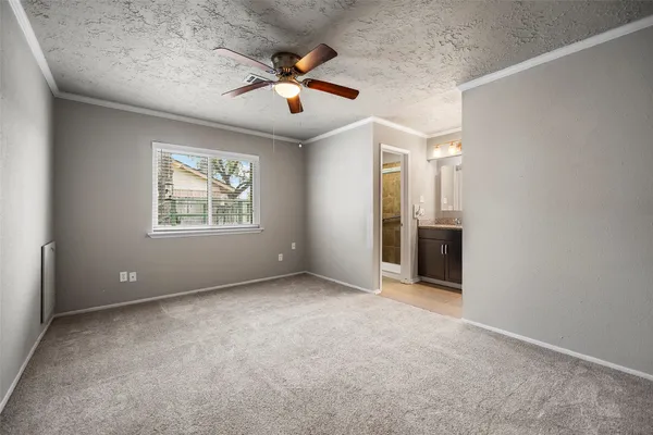 an empty room with chandelier fan and windows