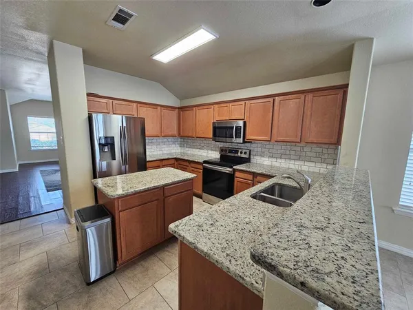 a kitchen with stainless steel appliances granite countertop wooden cabinets a stove a sink and a microwave