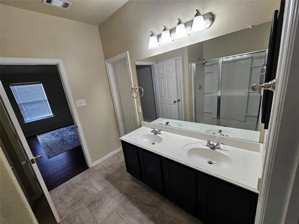 a en suite bathroom with a double vanity sink a mirror and a shower