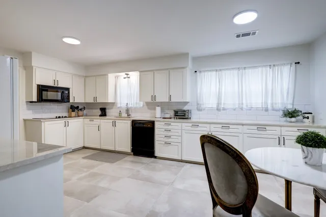 a kitchen with granite countertop white cabinets sink and stainless steel appliances
