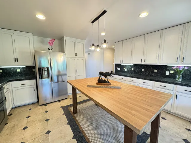 a kitchen with stainless steel appliances granite countertop a sink refrigerator and cabinets