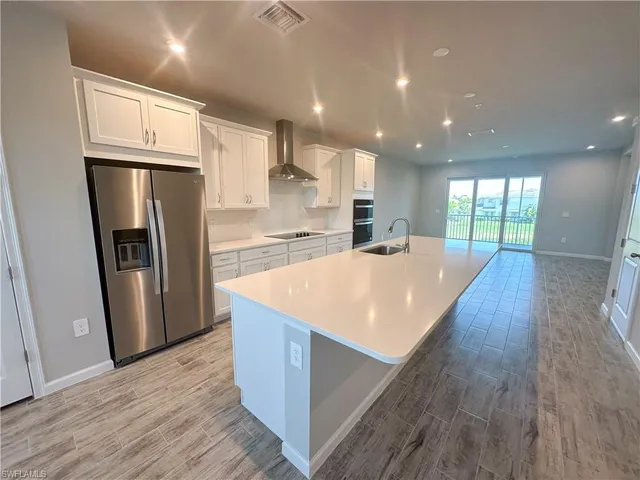 a large kitchen with stainless steel appliances a refrigerator and wooden floor