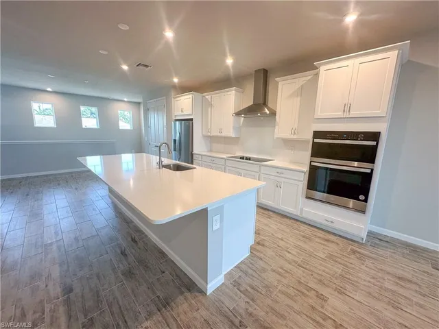 a kitchen with stainless steel appliances cabinets and wooden floor