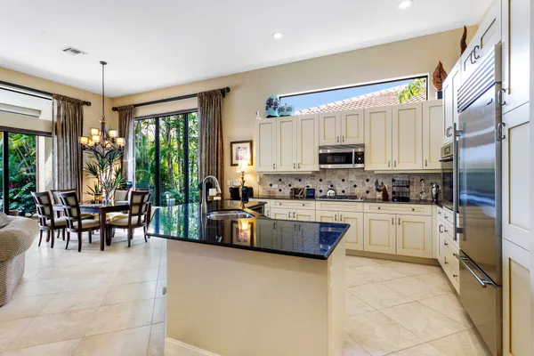 a kitchen with stainless steel appliances granite countertop a refrigerator a sink a stove and white cabinets