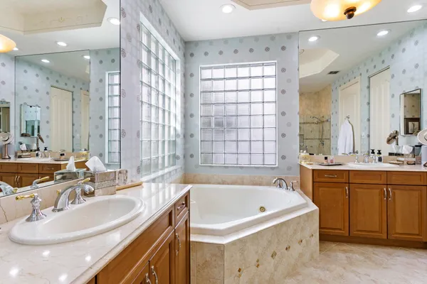 a bathroom with a sink double vanity granite tub shower and a mirror