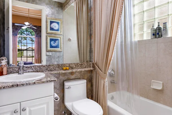 a bathroom with a granite countertop sink toilet and shower