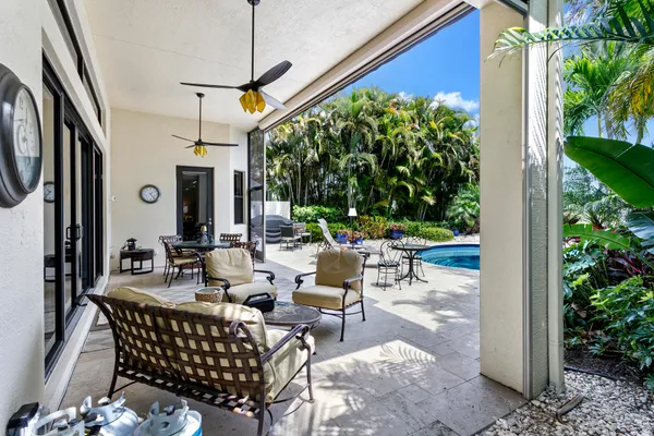 a view of a patio with couches table and chairs potted plants with wooden floor and fence