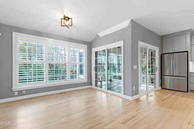 a view of an empty room with a window and wooden floor