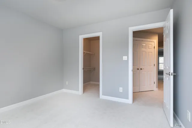 a view of an empty room with closet and a window